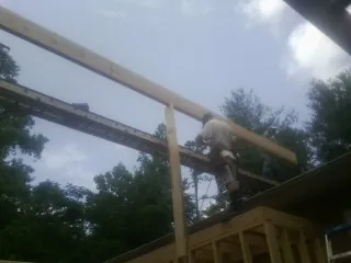 Carpenter setting a ridge beam over a new addition frame — Ice Dam Removal by Roofing Brothers in Paisley