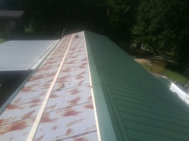 Old rusted panels beside newly installed green metal roofing — Wind Damage Roof Repair by Roofing Brothers in Paisley